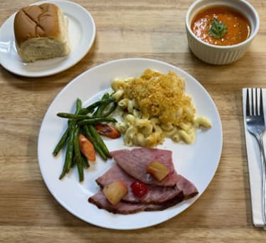 Plated holiday dinner with soup and a roll